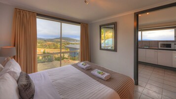 Habitación de hotel con una cama grande, vistas al campo, una zona de cocina y un espejo en la pared.