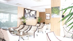 Un moderno vestíbulo de hotel con disposiciones para sentarse, un mapa del mundo y obras de arte enmarcadas.