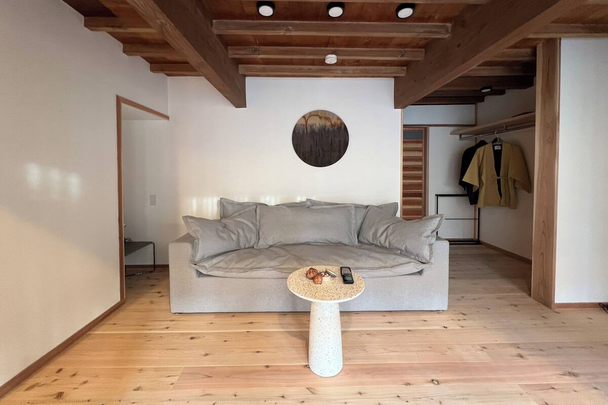 Ein modernes Wohnzimmer mit einem grauen Sofa, einem runden Couchtisch und einer Holzboden.