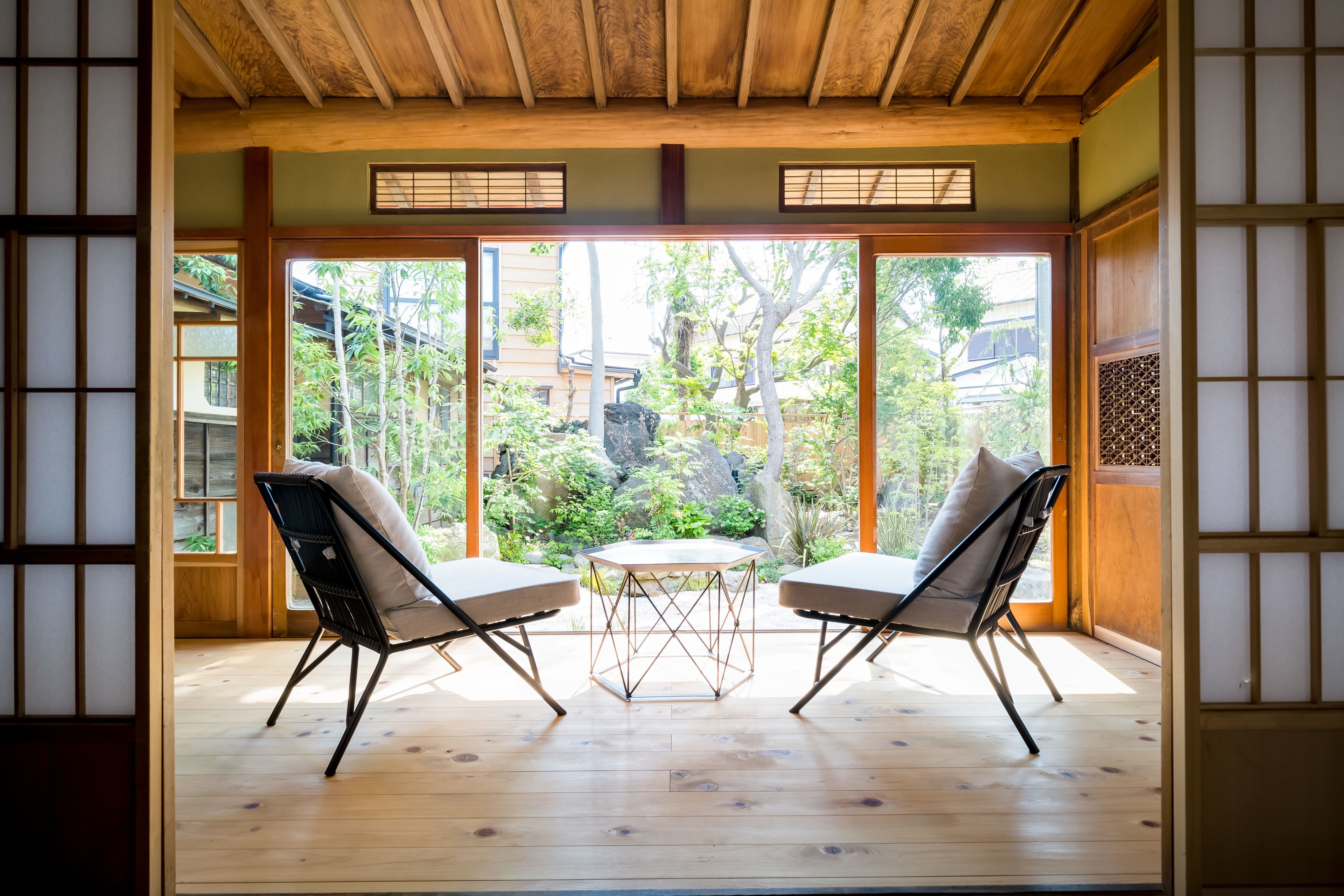 Una habitación japonesa tradicional con suelo de tatami, puertas correderas y vista a un jardín.