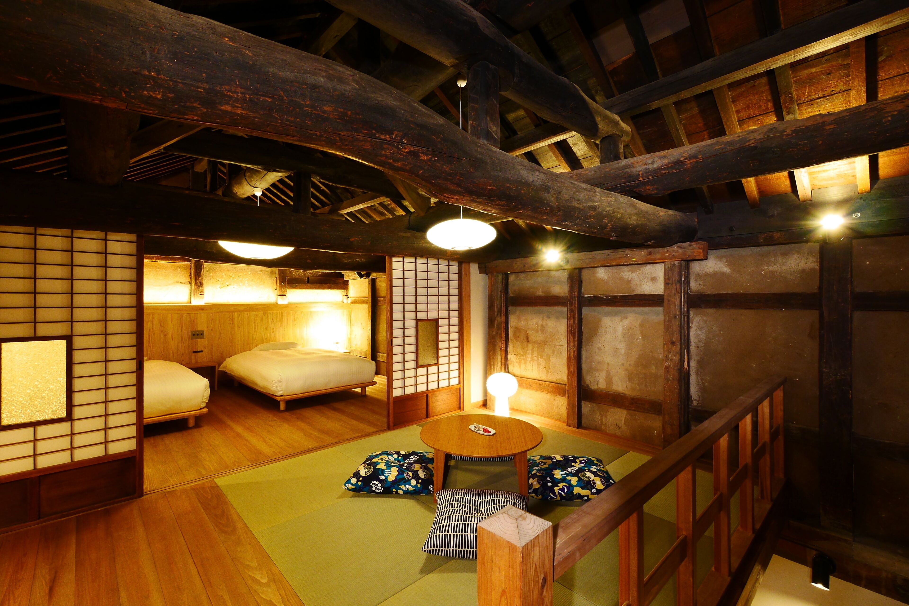 A traditional Japanese room with tatami flooring, a low wooden table, and futon beds.