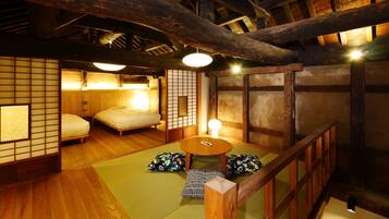 A traditional Japanese room with tatami flooring, a low wooden table, and futon beds.