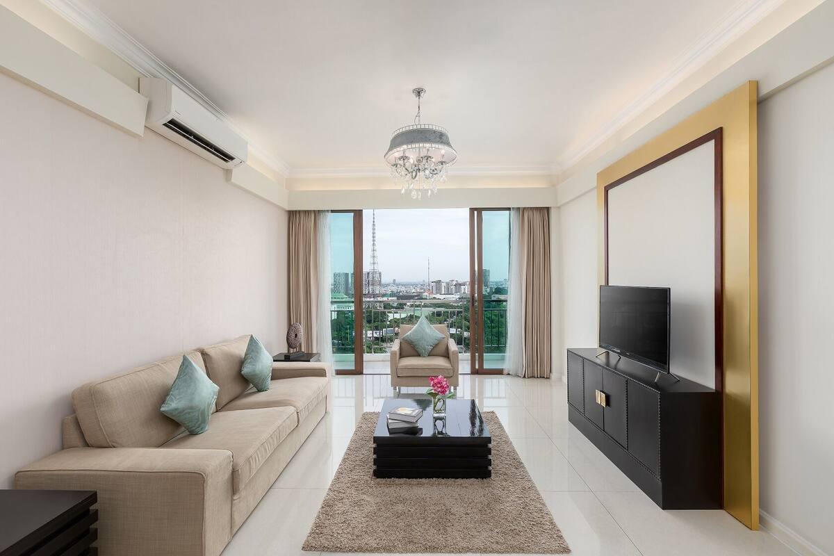 Un salon moderne avec un canapé, une table basse, un téléviseur et une vue sur le paysage urbain.