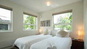 A hotel room with two beds, a nightstand with a lamp, and artwork on the wall.