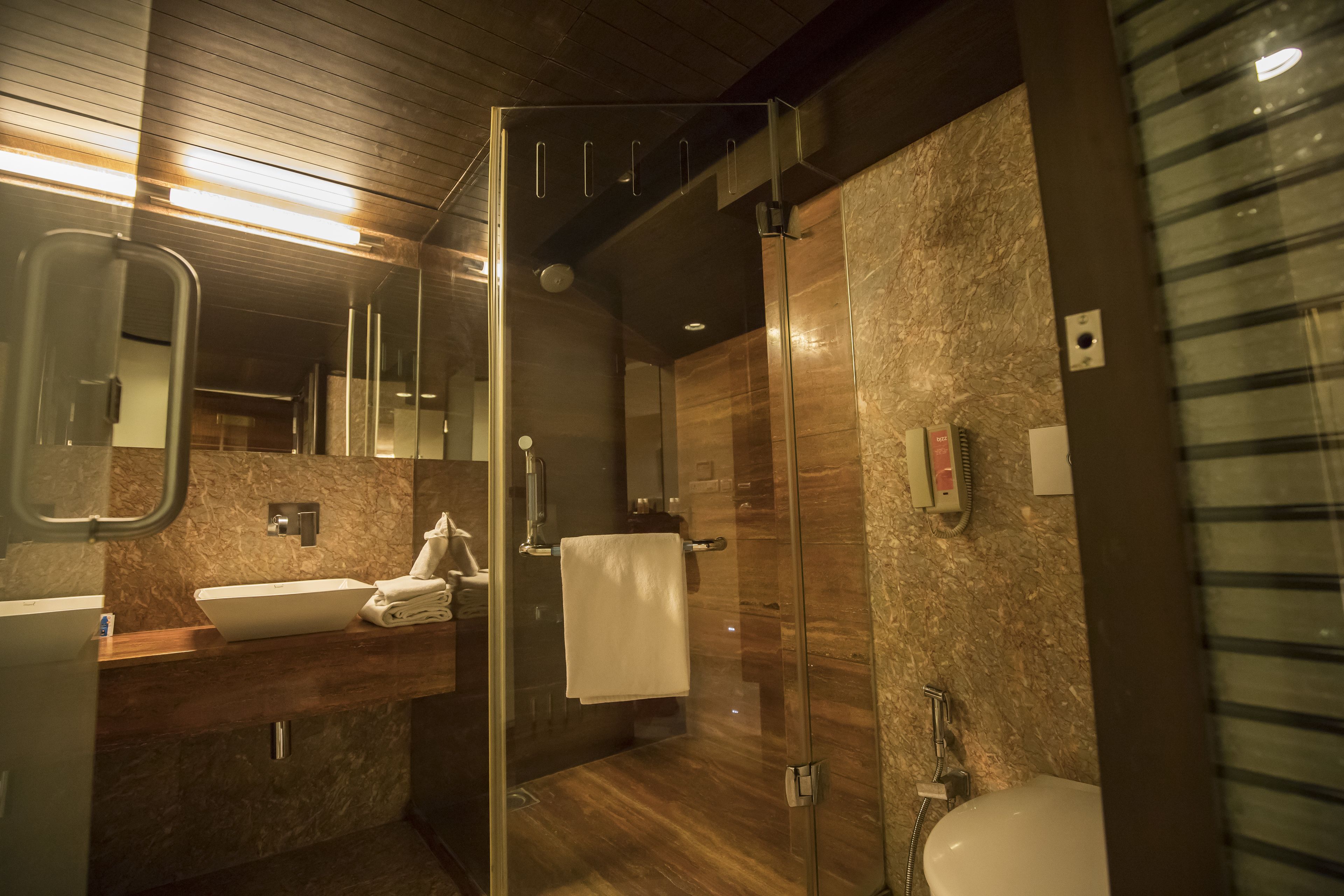 A modern bathroom with a glass-enclosed shower, a sink with a marble countertop, and a large mirror.