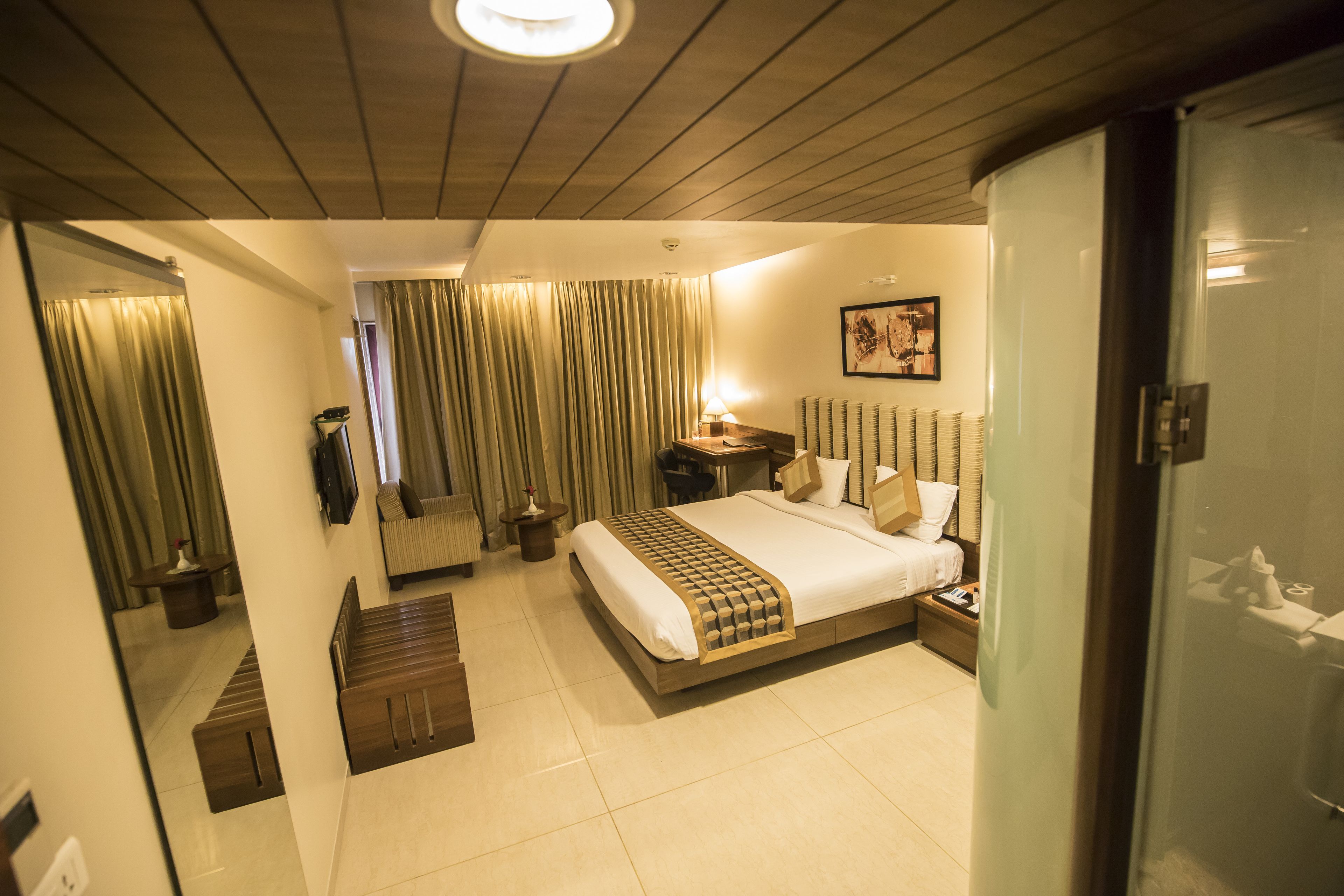 A modern hotel room with a large bed, bedside tables, a desk, and a mirror.
