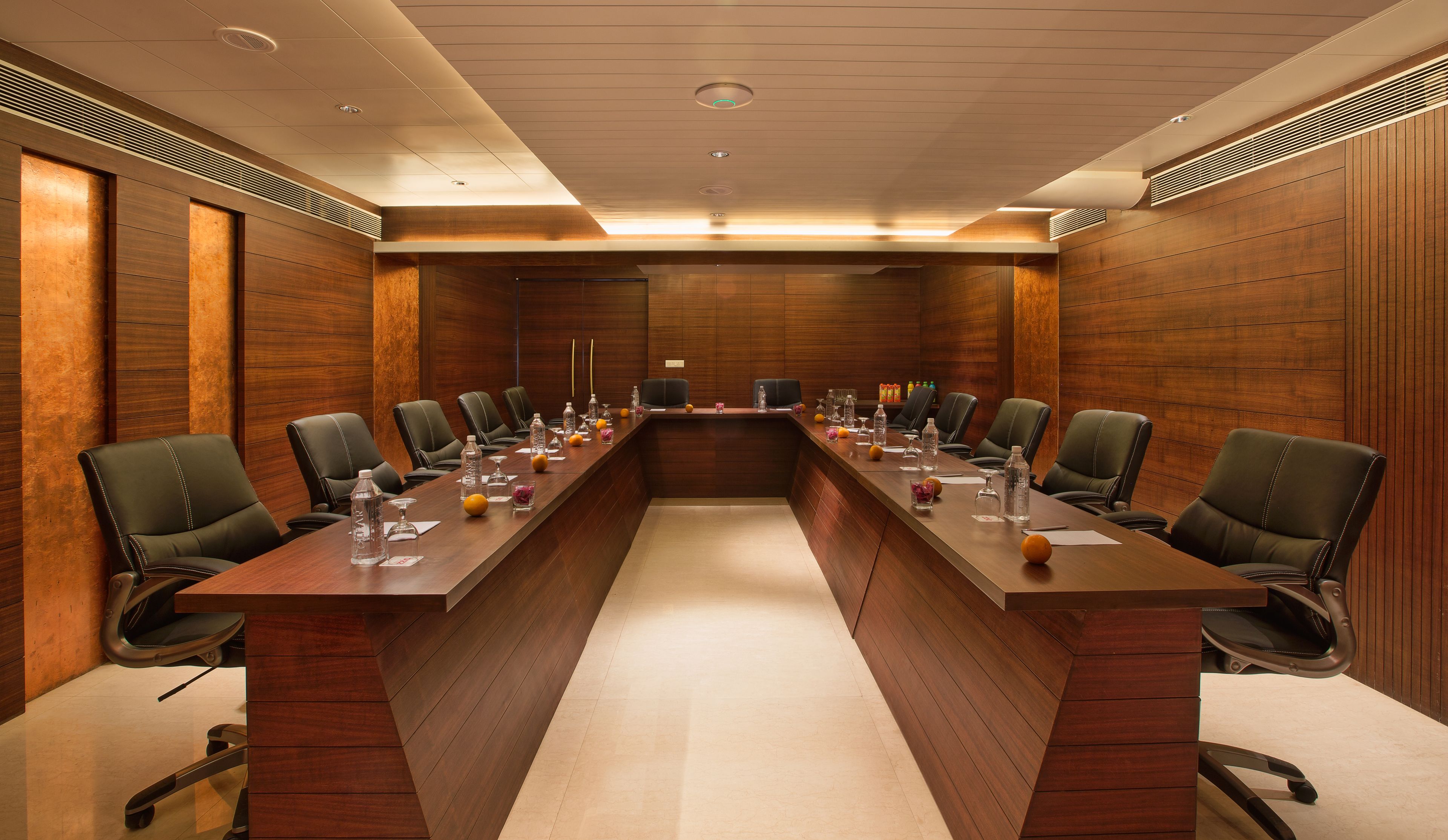 Une salle de conférence avec une longue table, des chaises et divers objets, comme des bouteilles d’eau et des verres.