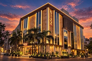 Um hotel moderno com uma placa grande chamativa com a inscrição 'bizz', janelas amplas e fachada bem iluminada.