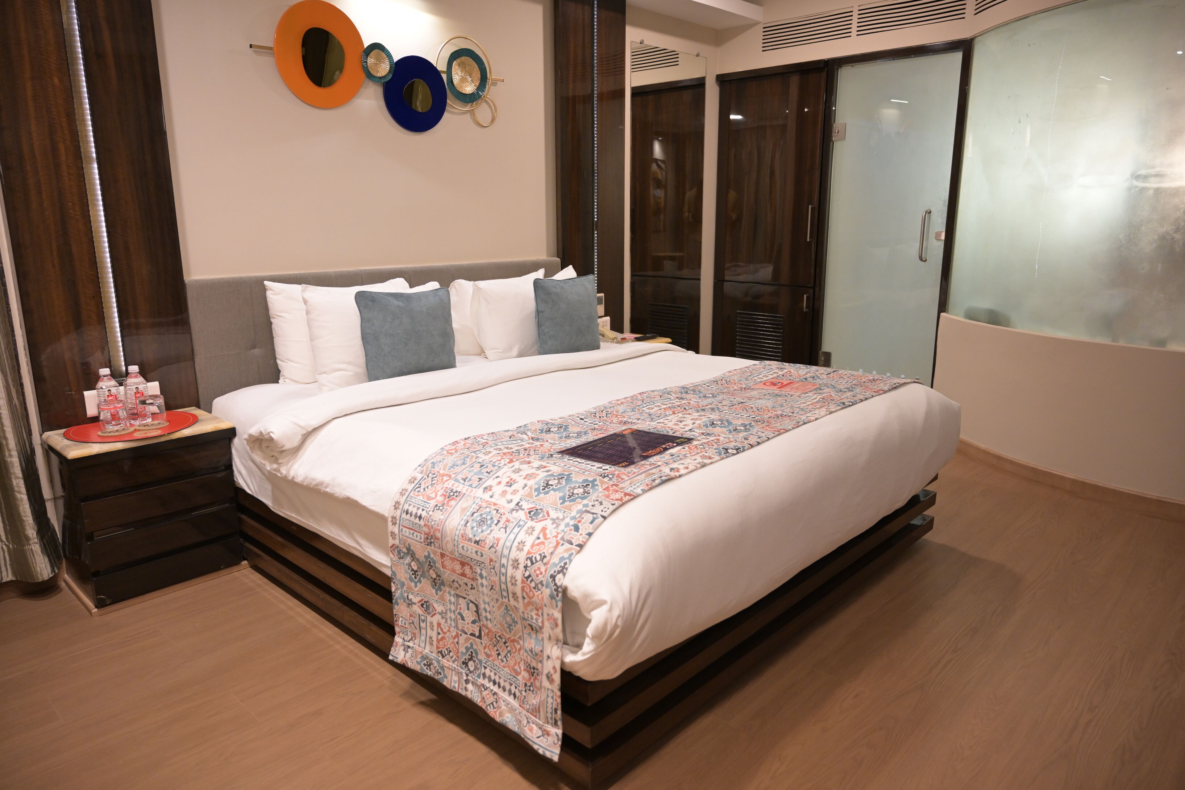 Una habitación de hotel con una cama grande, una mesita de noche con una bandeja roja y un espejo en la pared.