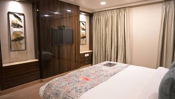 Una habitación de hotel con una cama grande, paneles de madera, un televisor de pantalla plana y una colcha estampada.