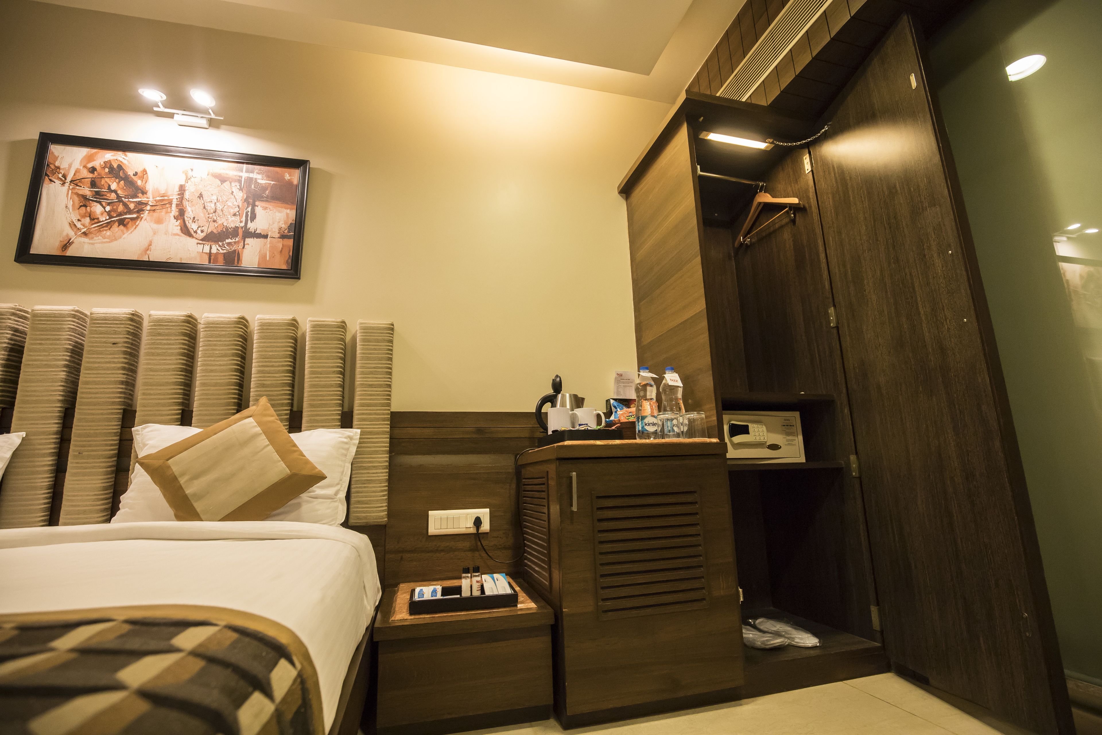 A hotel room with a bed, bedside table, and a wardrobe.