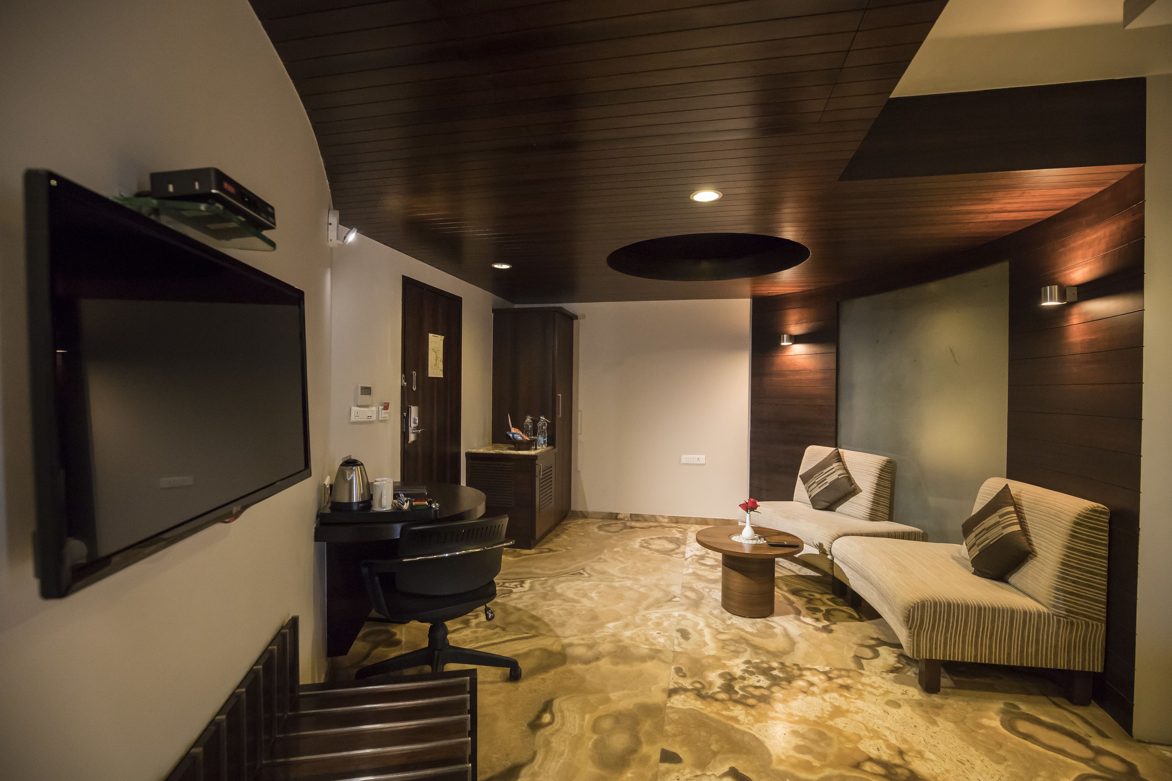 A modern living room with a flat-screen TV, a sofa, a coffee table, and a desk with a chair.