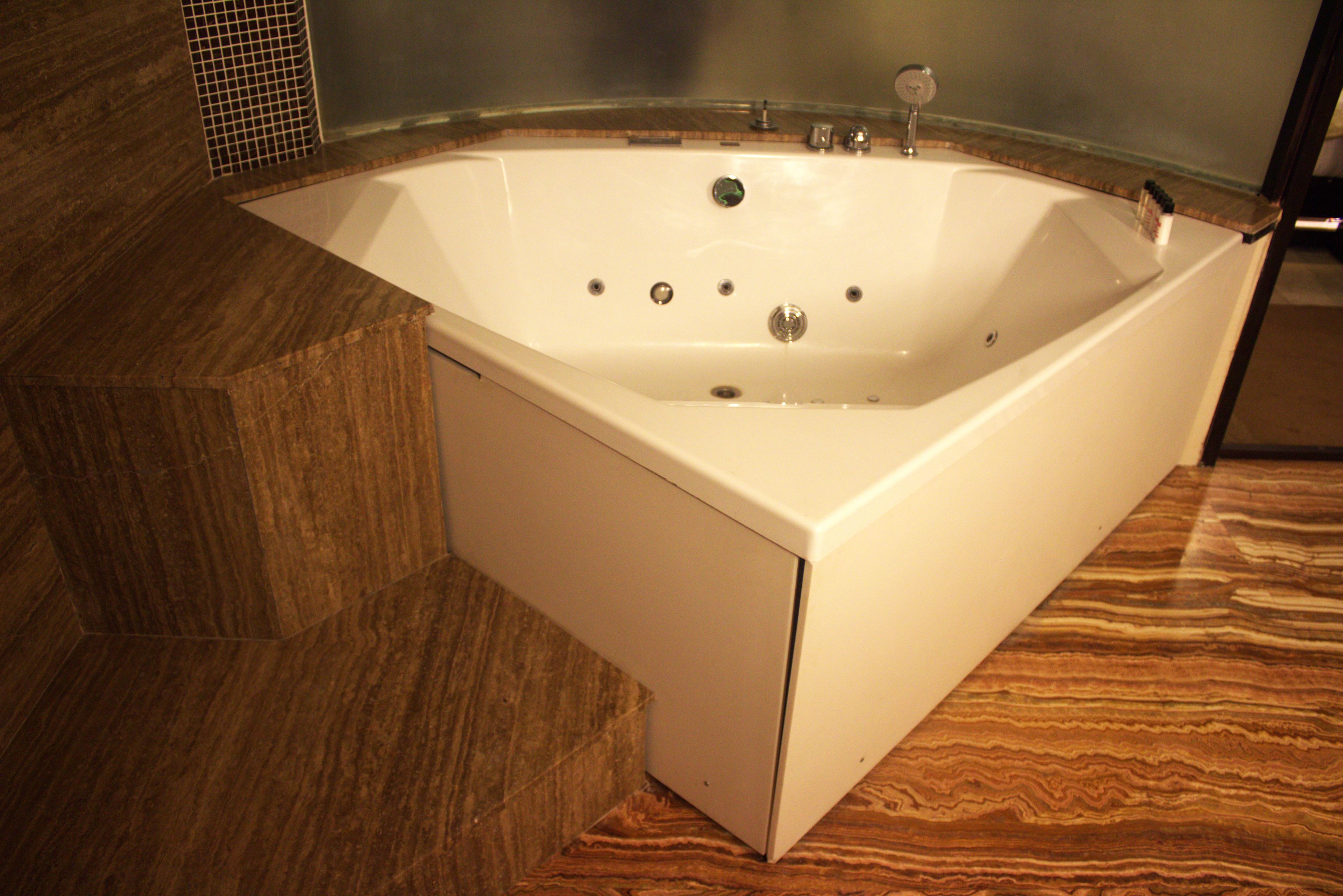A modern bathroom with a freestanding bathtub, a shower area, and a wooden floor.