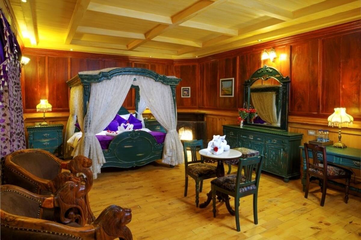 Une chambre à l’ancienne, dotée d’un lit à baldaquin, de meubles en bois et d’un lustre.