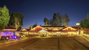 A hotel with a central courtyard, multiple guest rooms, and a well-lit entrance.