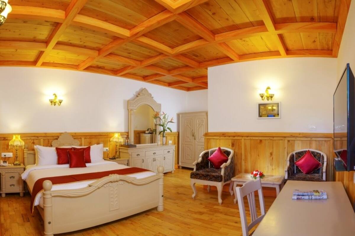Une chambre d’hôtel avec un plafond en bois, un lit avec des oreillers rouges, une table à manger et un miroir.