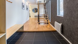 A modern interior with a wooden staircase, black tiled flooring, and a grey textured wall. - Ikigai (Kutchan)