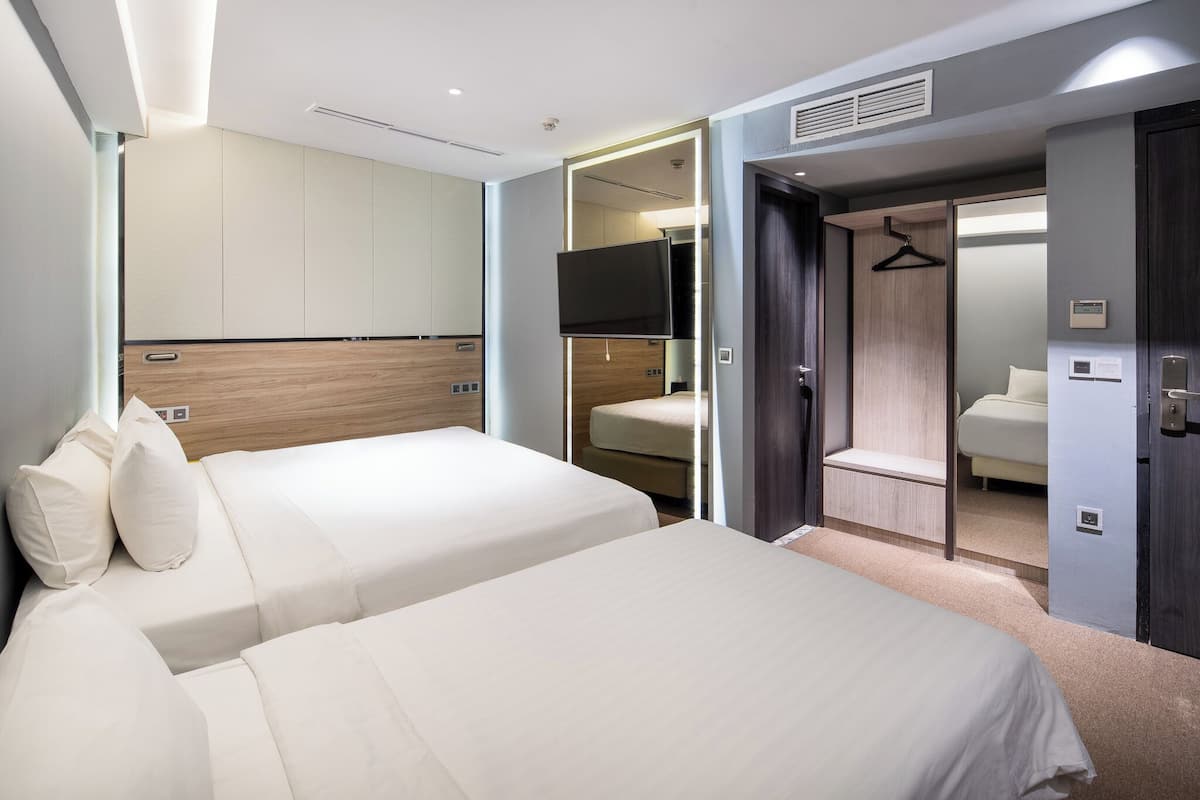 Quarto de hotel moderno com uma cama grande, uma TV e um closet espaçoso.