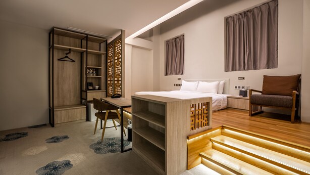 Un dormitorio moderno con cama, escritorio y silla. Se observa un armario con estantes y espacio para colgar ropa.