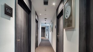 Un pasillo con puertas de madera oscura, una placa con el número 507, y un cuadro en la pared.