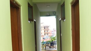 A hallway with wooden flooring and green walls, leading to a balcony with a railing. - Harry Guest House & Restaurant (Pokhara)