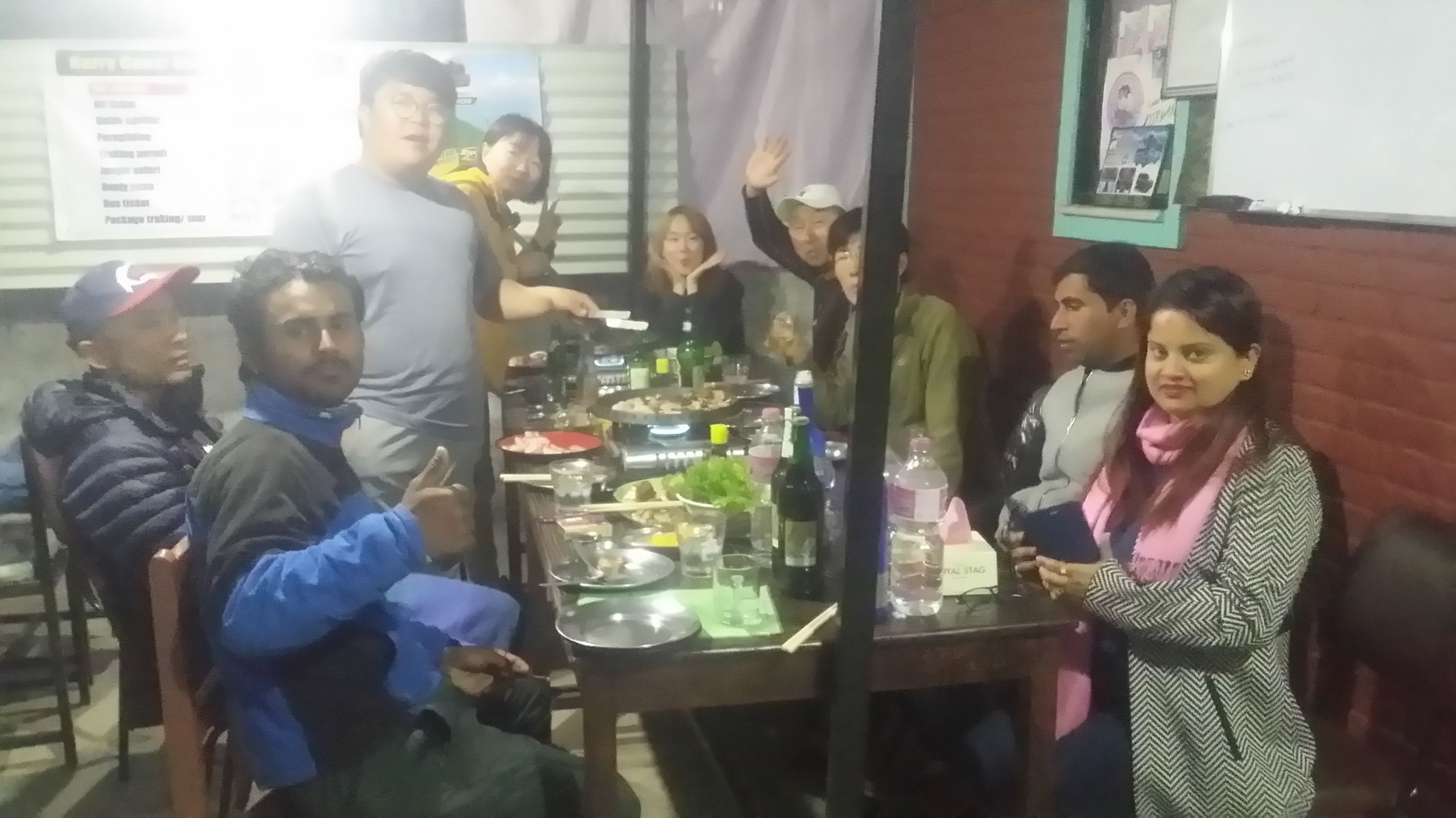 Un grupo de personas reunidas alrededor de una mesa con comida y bebidas, sugiriendo un evento social o una comida.