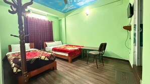 A room with two beds, a ceiling fan, a table, and a chair. - Harry Guest House & Restaurant (Pokhara)