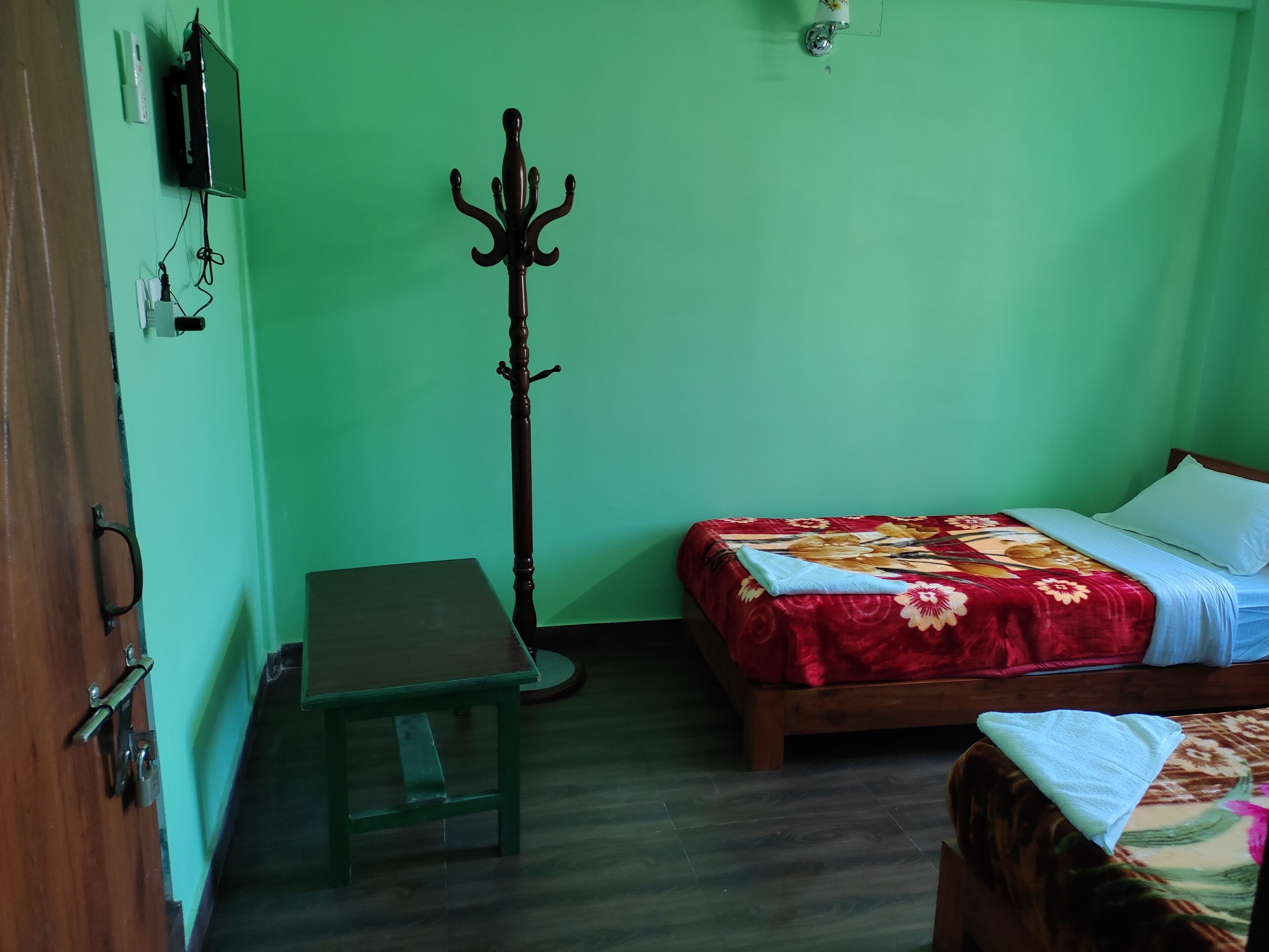 Una habitación con una cama, una mesa de madera y un perchero.