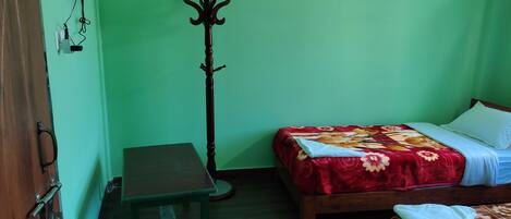 Una habitación con una cama, una mesa de madera y un perchero.