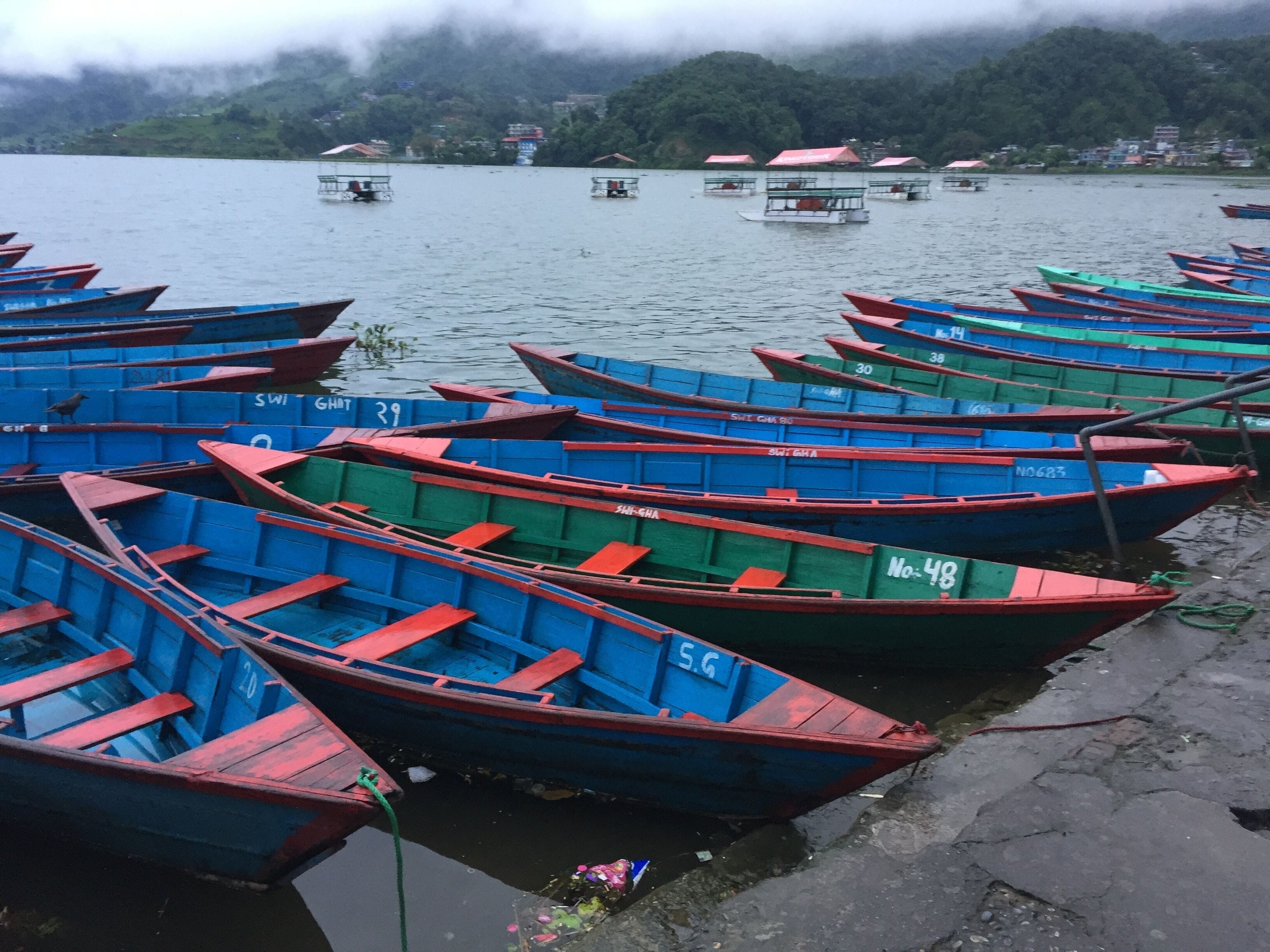 A row of colorful boats docked at a lakeside pier.