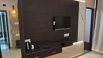 Una sala moderna con un televisor de pantalla plana, un espejo grande y un mueble de entretenimiento de madera.