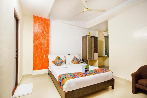 A hotel room with a bed, a chair, a wardrobe, and a bathroom.