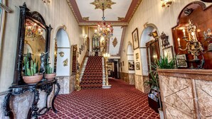 A grand hallway with a red carpet, ornate chandeliers, and a staircase leading to an upper level. - Grand Hotel de Londres (Istanbul)