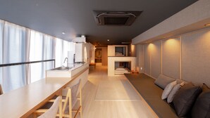 A modern kitchen with a dining area, a built-in seating area, and a small fireplace. - AET HOTEL (Tokyo)