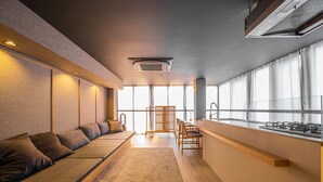 A modern kitchen with a long counter, wooden chairs, and a built-in stove. - AET HOTEL (Tokyo)