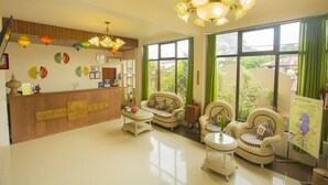A reception area with a wooden desk, wicker furniture, and a chandelier. - Inle Apex Hotel (Nyaungshwe)
