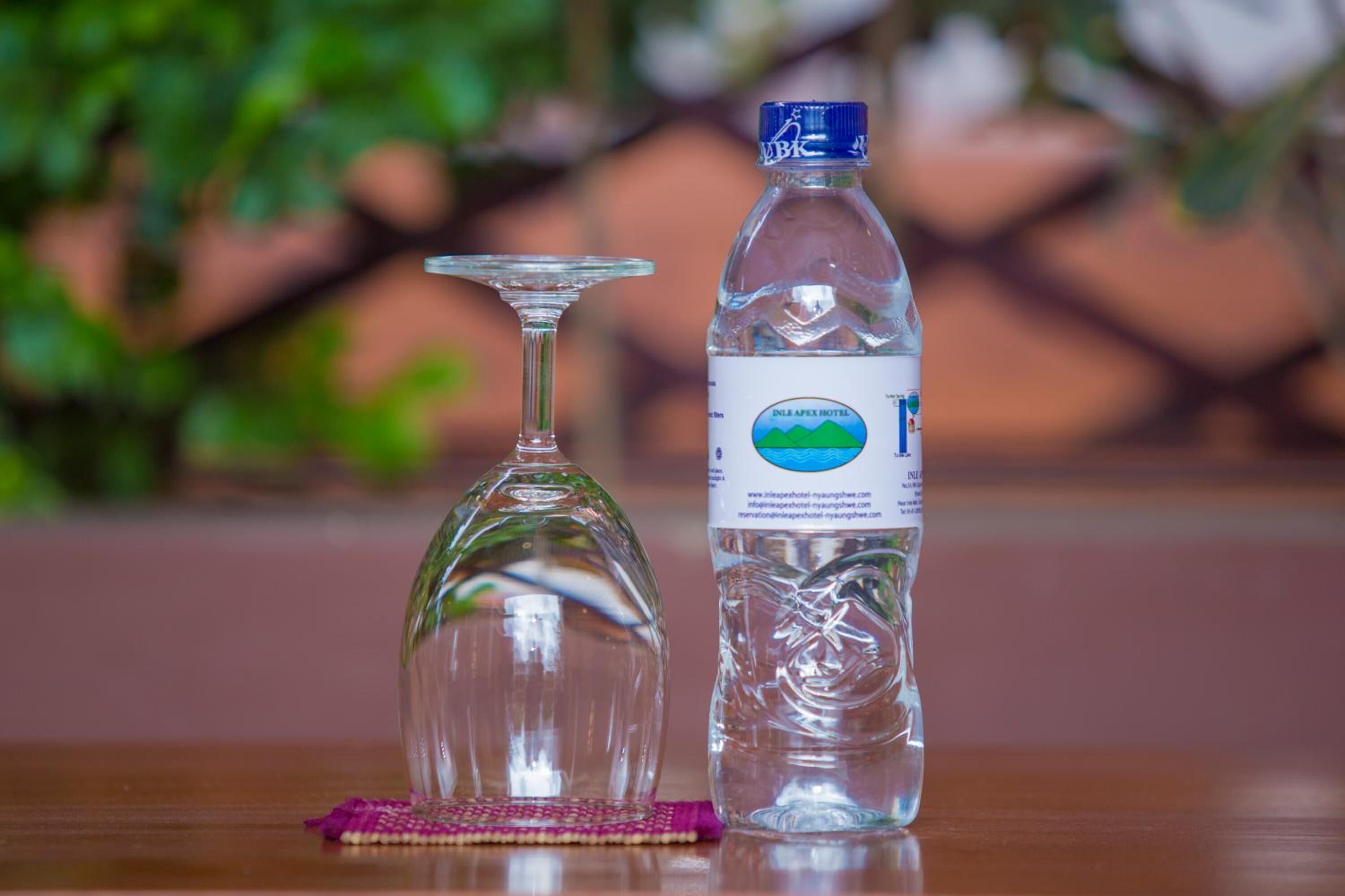 Ein klares Weinglas und eine Wasserflasche mit Etikett auf einer Holztischplatte.