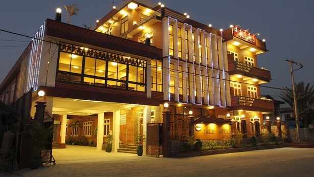 A multi-story hotel with a prominent entrance, large windows, and decorative lighting. - Inle Apex Hotel (Nyaungshwe)