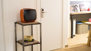 A room with a wooden floor, a metal shelf with a bag of rice, a vintage television, and a door with a modern lock. - 1970 Rooms (Naples)