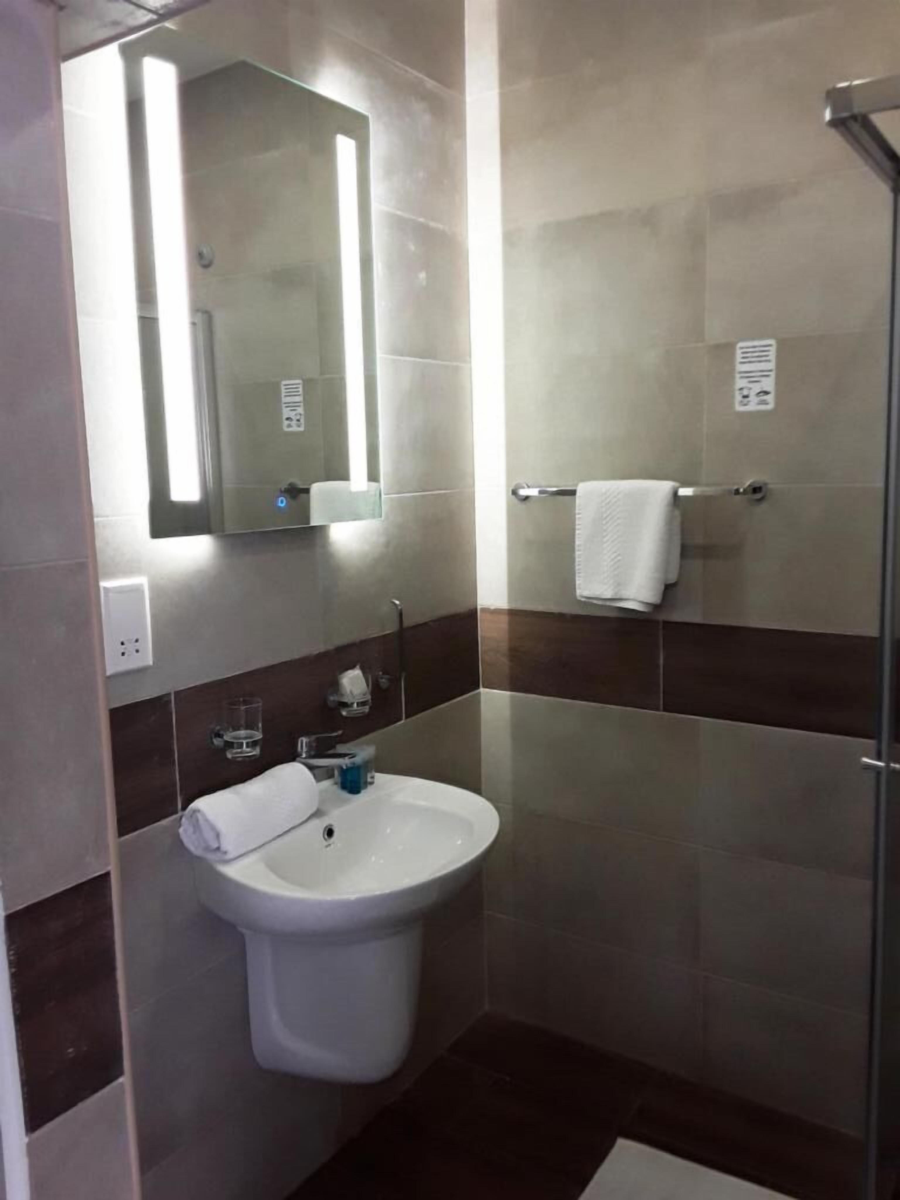 A bathroom with a white sink, a mirror, and a glass shower enclosure.