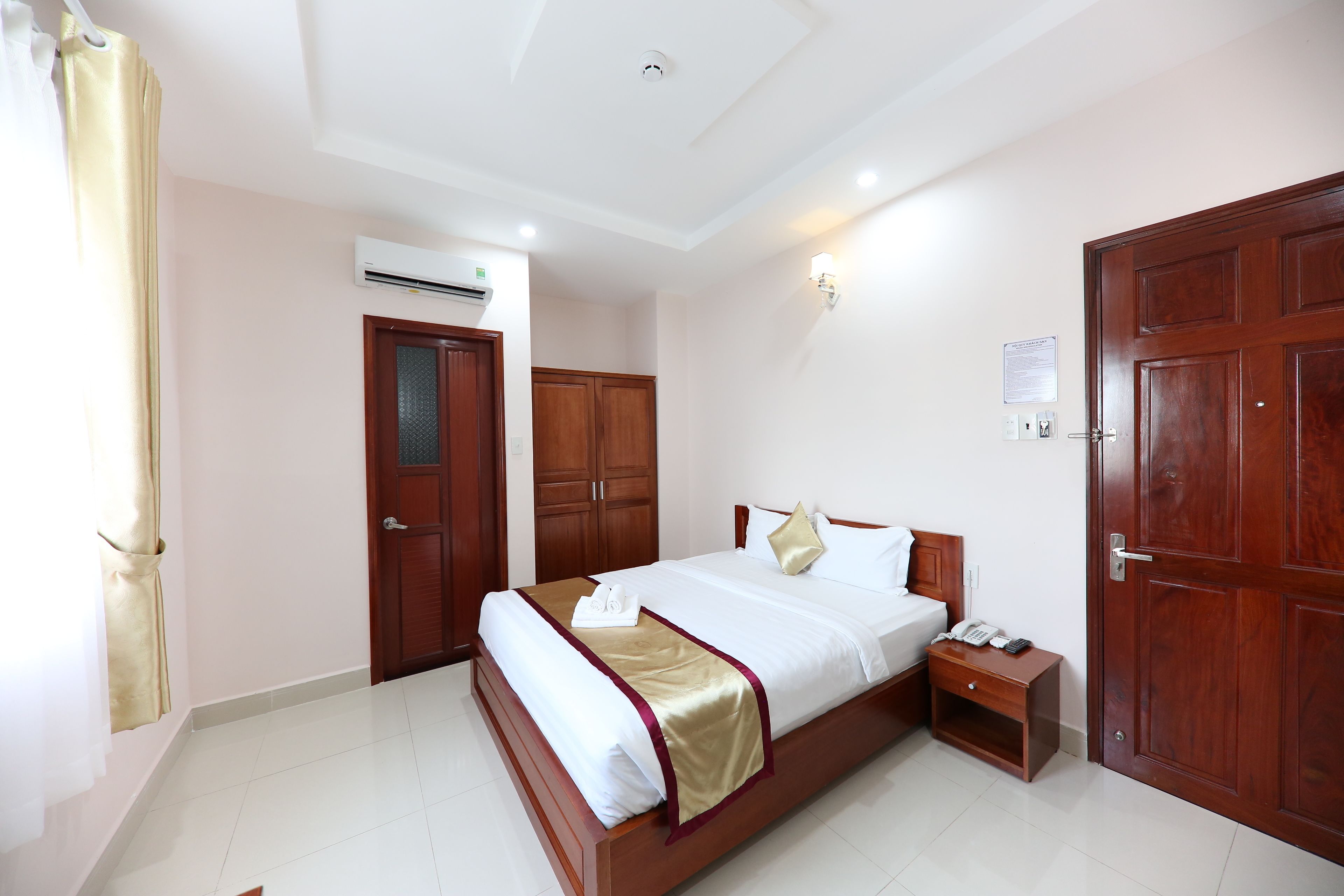 Une chambre d’hôtel avec un lit, une table de chevet et une armoire.