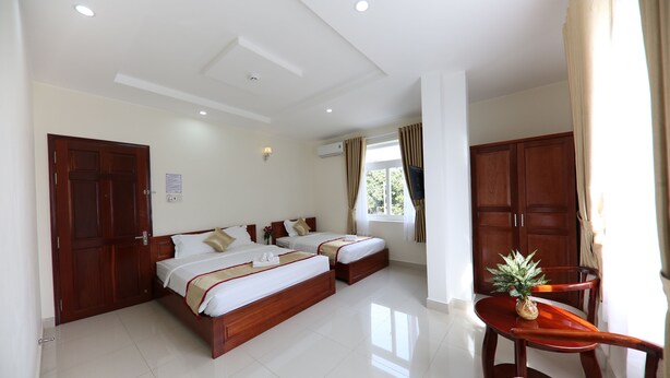 A hotel room with two beds, a wooden table, and a chair.