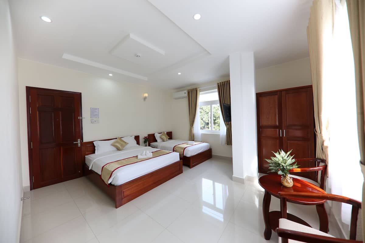 A hotel room with two beds, a wooden table, and a chair.