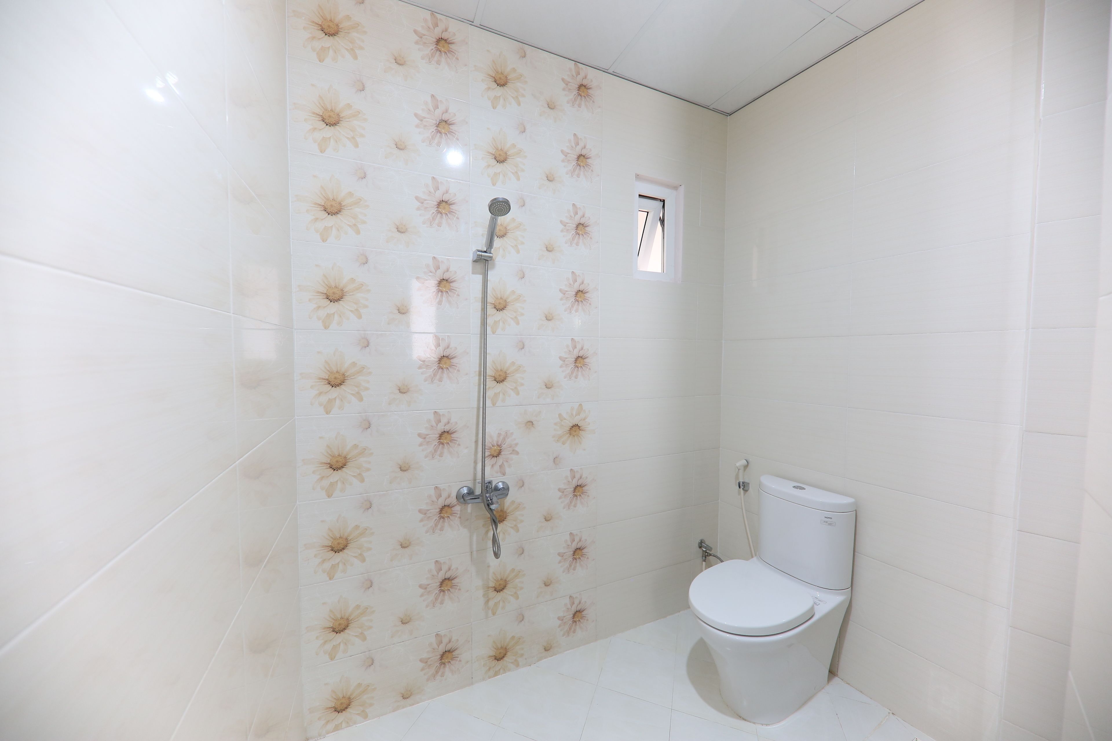 Un baño con ducha, inodoro y un pequeño ventanal.