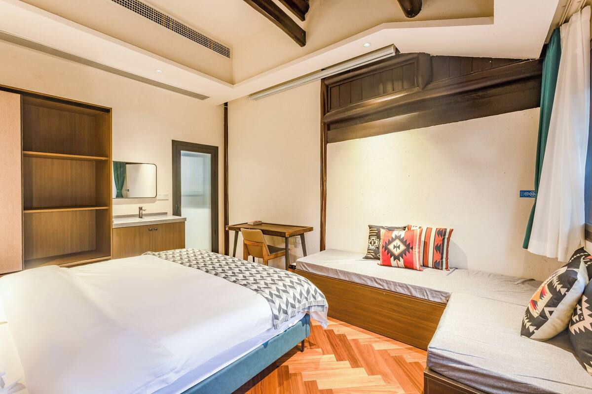 Een hotelkamer met twee bedden, een bureau, een spiegel en een kledingkast.