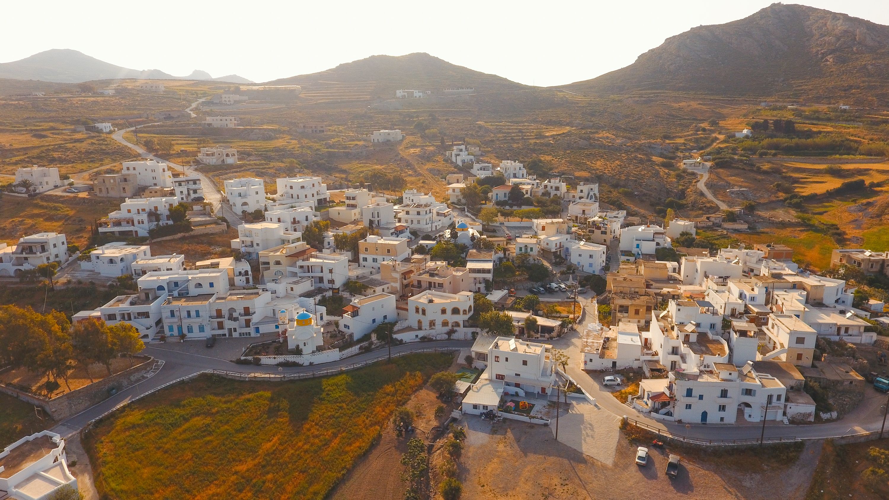 A coastal village with white buildings, narrow streets, and a mountainous backdrop.