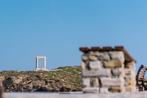 A stone structure with a rectangular frame on a hill, overlooking a body of water. - Villa Thimianos (Naxos)