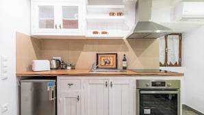 Eine Küche mit weißen Schränken, einem Edelstahl-Kühlschrank, einem Einbauofen und einer Arbeitsplatte mit Toaster und Wasserkocher.