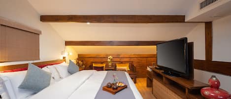 Une chambre d’hôtel avec un grand lit, une télévision et une tête de lit en bois.