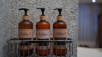 Three bottles of Kalahari London soap on a metal shelf against a speckled wall.